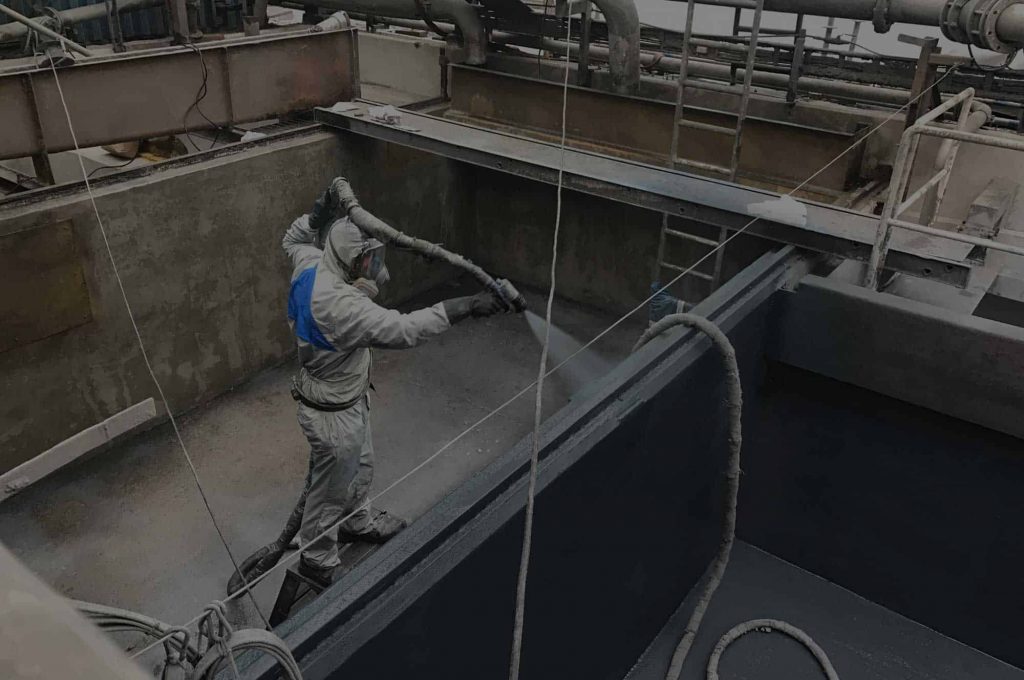 Applicator spraying a tank lining
