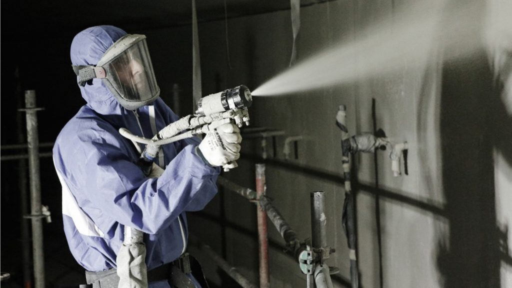 Applicator spraying a protective coating on a wall